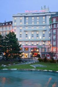 a large building with a river in front of it at Mercure Lourdes Impérial in Lourdes