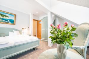 - une chambre avec un lit et un vase de fleurs sur une table dans l'établissement Hotel Villa Neander, à Binz