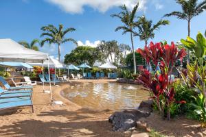 una piscina con sillas y sombrillas en una playa en Kiahuna Plantation Hale, en Koloa