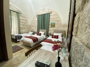 a bedroom with two beds and a table with a vase of flowers at Ma'an lil-Hayat Boutique Hotel in Bethlehem