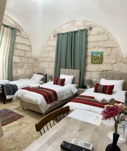 a bedroom with two beds and a table with a computer at Ma'an lil-Hayat Boutique Hotel in Bethlehem
