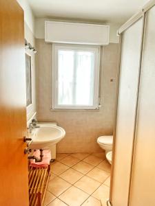 een badkamer met een wastafel, een toilet en een raam bij Villetta Audrey al Mare in Riccione