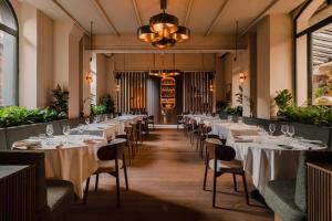 a row of tables in a restaurant with white table settings at Aethos Milan in Milan