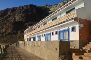 un edificio con porte blu e una montagna di Apartamentos Playa Azul a Vallehermoso