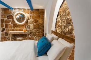 een slaapkamer met een bed en een stenen muur bij Santorini in Akko