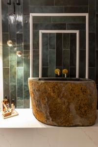 uma casa de banho com uma grande banheira de pedra em frente a um chuveiro em Santorini em Acre