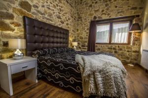 1 dormitorio con 1 cama grande y pared de piedra en Apartamentos Baolafuente, en Rasines