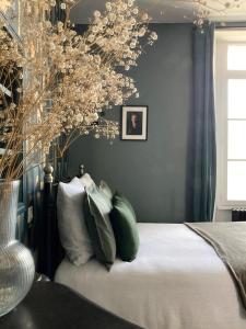 a bedroom with a bed with green and white pillows at Logis « Henriette » • Maison du XVe siècle in Provins