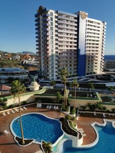 een hotel met een zwembad voor een hoog gebouw bij Brand new apartment Club Paraiso Ocean view in Playa Paraiso