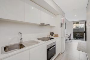 a white kitchen with a sink and a stove at The Merchant Hotel in Sydney