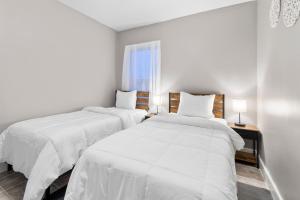 two beds in a white room with a window at Vida Comfy Inn 3 bedroom Apartment 8 mins to downtown and ferry in New Bedford