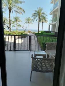 a balcony with two chairs and a table and palm trees at Two Bedrooms Apartment at Address Residence Fujairah in Sharm