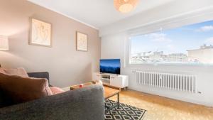 ein Wohnzimmer mit einem Sofa, einem TV und einem Fenster in der Unterkunft HOMEY PINKY - Proche Centre / Balcon privé / Wifi in Annemasse