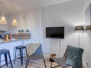 kuchnia z dwoma krzesłami i bar z telewizorem na ścianie w obiekcie Apartment L'Ile heureuse-7 by Interhome w mieście Saint-Cyr-sur-Mer