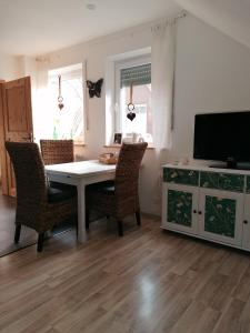 comedor con mesa, sillas y TV en Ferienwohnung Mühlenbachhexe, en Lingen