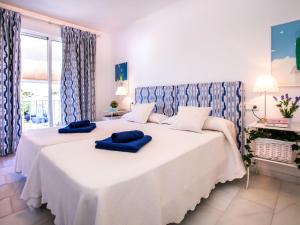 a bedroom with a large white bed with blue pillows on it at Apartment Jardine de Bolonia Plus by Interhome in Jávea