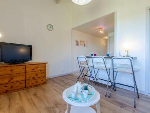 een woonkamer met een tv en een tafel en stoelen bij Apartment Les Bourdaines by Interhome in Seignosse