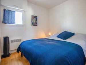 sypialnia z łóżkiem z niebieskimi prześcieradłami i oknem w obiekcie Apartment La Louisiane by Interhome w mieście Capbreton
