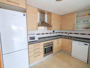 a kitchen with wooden cabinets and a white refrigerator at Apartment Golden Beach by Interhome in Sant Carles de la Ràpita