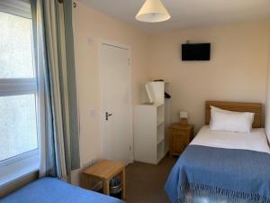 Habitación pequeña con 2 camas y ventana en Martyrs Bay Rooms en Iona