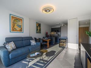 a living room with a blue couch and a kitchen at Apartment Les Villas du Men Du-3 by Interhome in Carnac