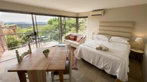 a bedroom with a bed and a table and a balcony at Orangerie Guest House in Johannesburg