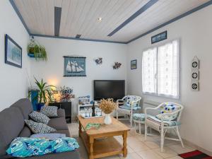 sala de estar con sofá, sillas y TV en Holiday Home La Glycine by Interhome, en Lampaul-Plouarzel