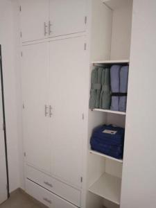 ein weißer Schrank mit weißen Schränken und blauen Handtüchern in der Unterkunft Departamento para 4 personas con cochera in Godoy Cruz