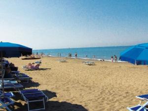 a beach with blue umbrellas and people in the water at Holiday Home Camping Free Beach by Interhome in Marina di Bibbona