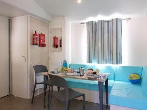 a dining room with a blue couch and a table at Holiday Home Camping Free Beach by Interhome in Marina di Bibbona