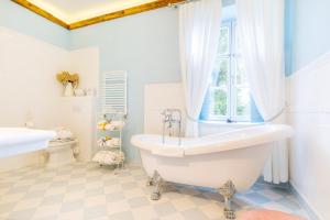 a bathroom with a tub and a toilet and a window at Folwark Karczemka in Małdyty