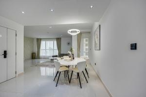 uma sala de jantar branca com uma mesa e cadeiras brancas em Bright stylish sea view apartment in JBR em Dubai