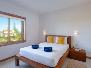 a bedroom with a large white bed with blue pillows at Villa Almond Tree by Interhome in Porches +26 photos