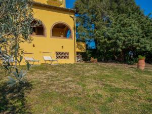 uma casa amarela com duas cadeiras num quintal em Holiday Home Bellavista by Interhome em Riparbella