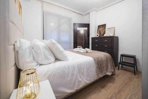 a bedroom with a white bed and a dresser at La Muralla centro Oviedo in Oviedo