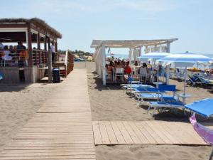 a boardwalk on the beach with chairs and umbrellas at Holiday Home Camping Village Free Time by Interhome in Marina di Bibbona