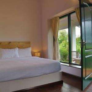 um quarto com uma cama e uma grande janela em The Tamarillo em Ooty