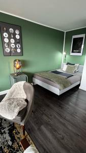 - une chambre avec des murs verts, un lit et une chaise dans l'établissement BOSTEL 54 - Moderne Stadtwohnung in Moers-Zentrum, à Moers
