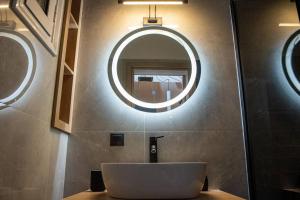 La salle de bains est pourvue d'un lavabo et d'un miroir rond. dans l'établissement Mike's studio, à Vólos