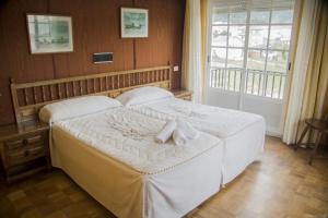 een slaapkamer met een bed met witte lakens en een raam bij As Areas II in Viveiro