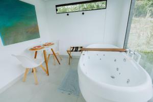 a white bathroom with a bath tub and a table at Reserva Cabanas in Balsa Nova