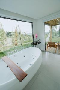 a white bath tub in a room with a large window at Reserva Cabanas in Balsa Nova