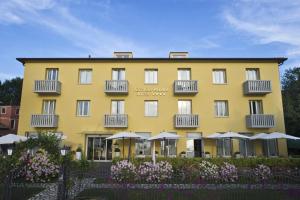 ein gelbes Gebäude mit Sonnenschirmen davor in der Unterkunft Viktoria Palace Hotel in Lido di Venezia