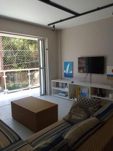 Il comprend un salon doté d'un canapé et d'une télévision à écran plat. dans l'établissement Apartamento familiar com acesso privativo à Praia Mansa, à Matinhos