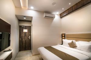 a hotel room with a bed and a television at Hotel Royal Treat Surat in Surat +14 photos