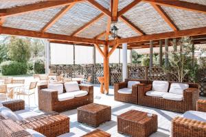 un patio con sillas y mesas de mimbre y pérgola de madera en VALTUR OTIUM RESORT en Villapiana