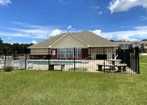 a house with a fence in front of a yard at Boll Weevil Cottage in Enterprise