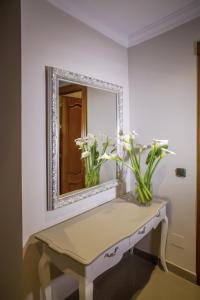 a mirror on a wall above a table with flowers on it at Hotel Bajamar Centro in Nerja