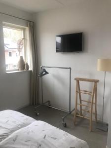 een slaapkamer met een stoel en een televisie aan de muur bij B&B Achterhoeks Halle in Halle