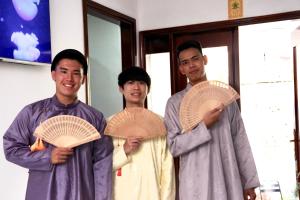 a group of three men holding up wooden plates at LaLa Citadel Homestay in Hue